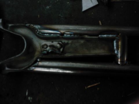 1978 Ford Bronco - A close-up view of a metal suspension part, likely a radius arm, showing signs of modification and welding.