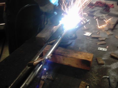 1978 Ford Bronco - A close-up view of a metal part being welded, with sparks flying in a workshop environment.