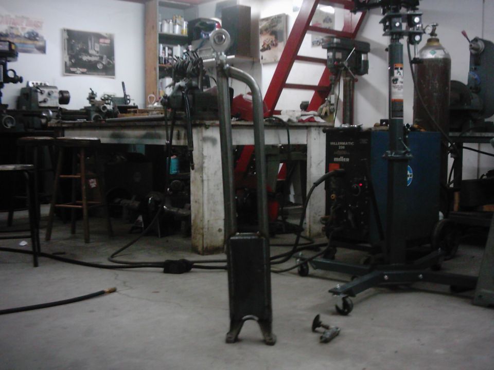 Workshop scene with metal fabrication equipment, including a welding machine and a drill press