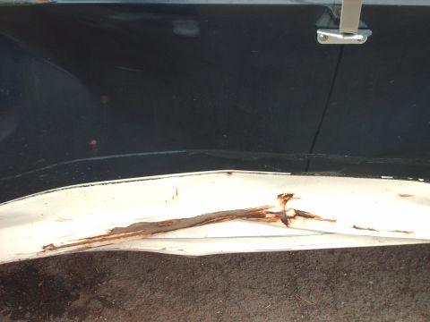 1988 Ford Bronco - Close-up of damaged white trim and rust on a dark blue vehicle.