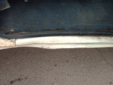 1988 Ford Bronco - Close-up view of the interior door sill and carpet of a vehicle, showing wear and tear.
