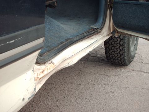 1988 Ford Bronco - Close-up of a vehicle's damaged door sill and tire, with a Supermotors logo in the corner.