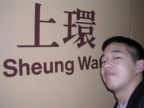 1999 Toyota Tacoma - A man stands next to a sign that reads "Sheung Wan" in English and Chinese characters.