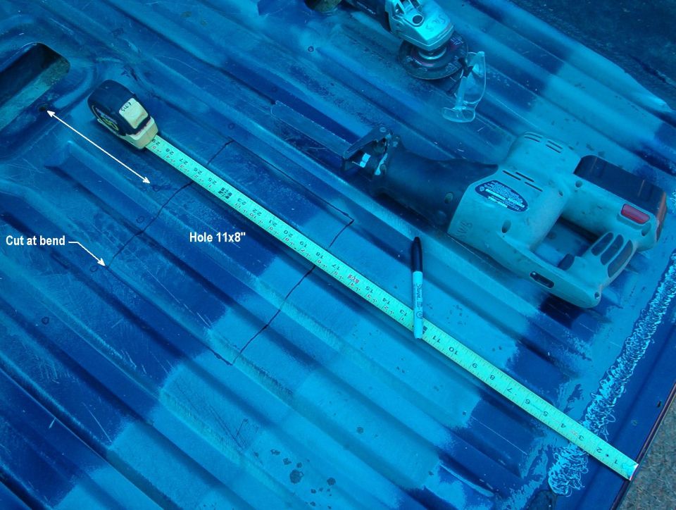 Blue corrugated truck bed floor with tape measure marking an 11x8 inch hole and reciprocating saw