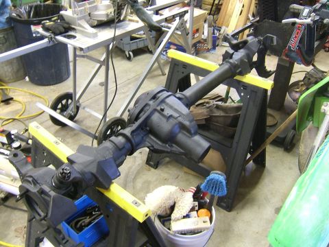 1993 Ford Bronco - A vehicle axle assembly is supported by sawhorses in a workshop setting, with tools and equipment in the background.