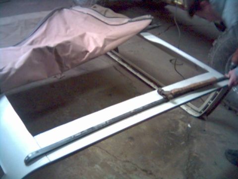 1986 Ford Bronco - A white soft top frame with a tan cover is visible, along with a tool resting on it.