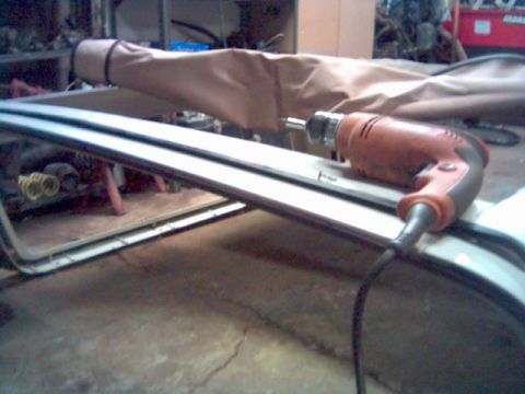 1986 Ford Bronco - Drill positioned on a vehicle's roof frame, possibly for repair or modification.