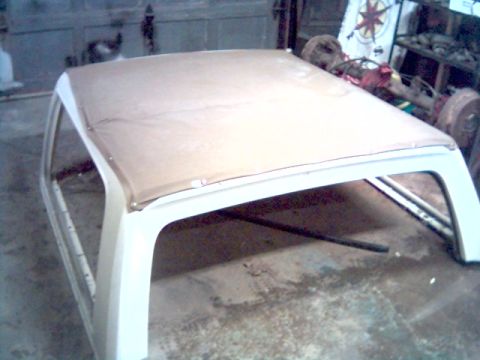 1986 Ford Bronco - The tan soft top frame of a vehicle is shown in a garage setting.