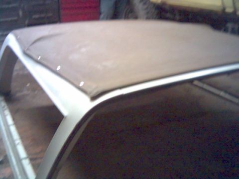 1986 Ford Bronco - The frame of a soft top convertible is visible, with a tan fabric cover attached.