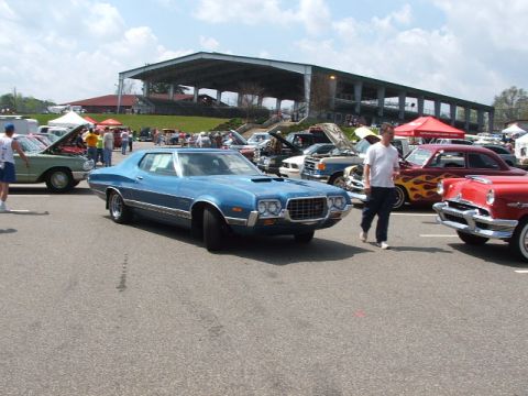 1966 Ford Ranchero - A blue 1972 Ford Gran Torino Sport is displayed at a car show, with other vehicles and spectators in the background.