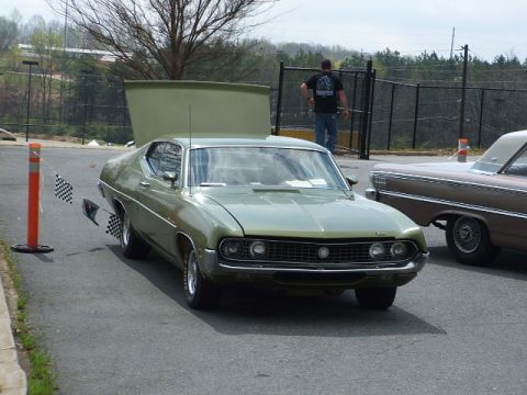 1966 Ford Ranchero - A green 1970 Ford Torino is displayed with its hood up, next to another classic car.