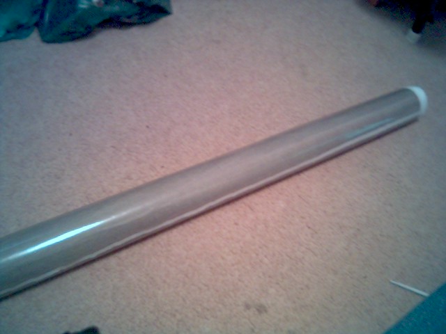Silver metal tube with white end cap on carpeted floor