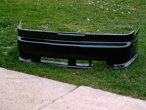 1995 Ford Probe - A black rear bumper is shown on a grassy area next to a concrete path.