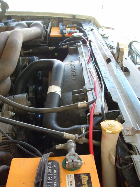 1990 Ford Bronco - Engine bay view down the passenger side showing two yellow-cased Duralast batteries installed in a dual-battery setup, one in the foregroun…