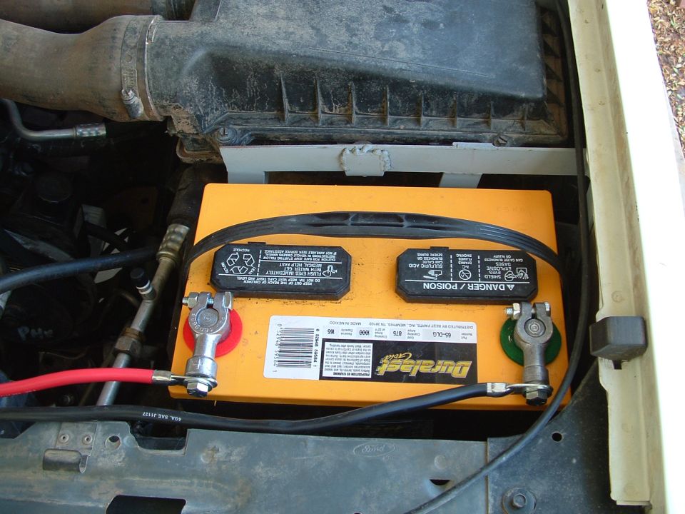Orange Duralast Gold battery in engine bay with top-post terminals and heavy gauge cables