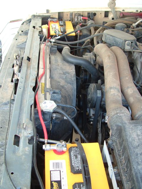 1990 Ford Bronco - Close-up view of an engine bay showing dual battery setup and engine components.