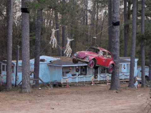 1996 Ford F-150 - A red car is loaded onto a trailer, with trees and a structure visible.