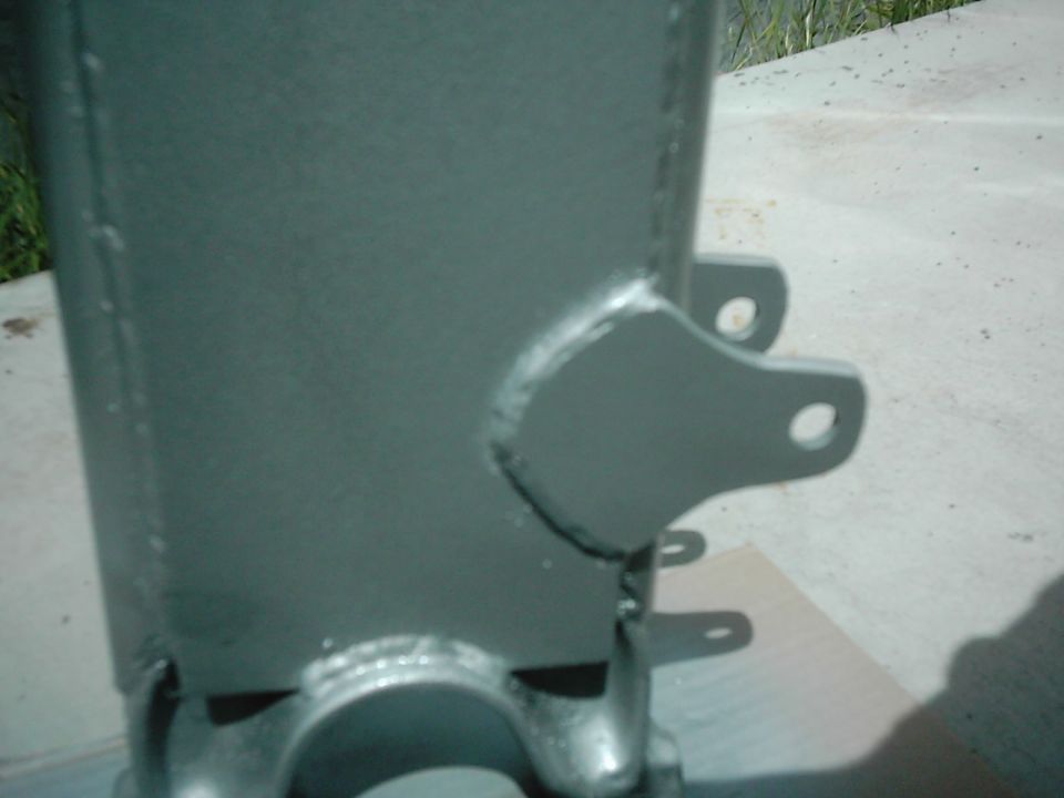 Close-up of a gray painted metal suspension part with mounting holes