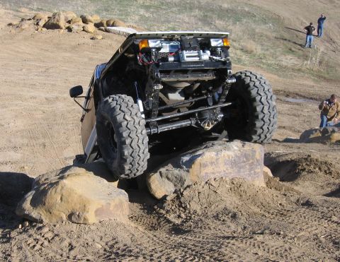 1981 Ford Bronco - Modified off-road vehicle navigates a rocky obstacle course with its hood open.