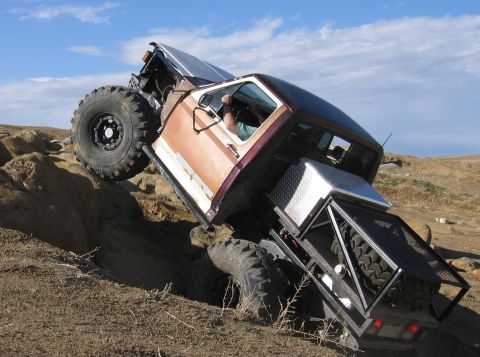 1981 Ford Bronco - This heavily modified truck is navigating a challenging rocky terrain with its large off-road tires.