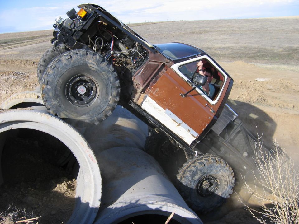 Brown 1981 Ford Bronco climbing over concrete pipes
