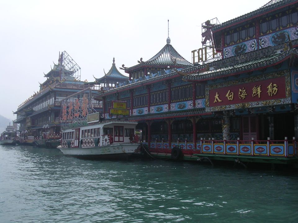 Floating restaurants and boats docked on the water, with ornate Chinese architecture visible