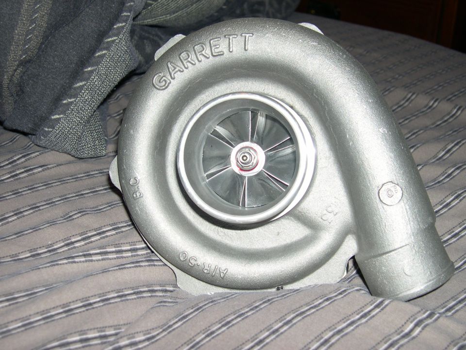 Silver Garrett turbocharger with "AIR-50" and "33" cast into its housing, resting on a striped fabric