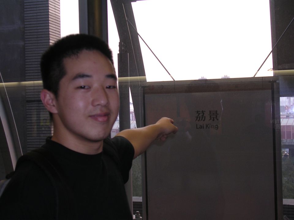 Man in black shirt points to a sign with Chinese characters and "Lai King" text