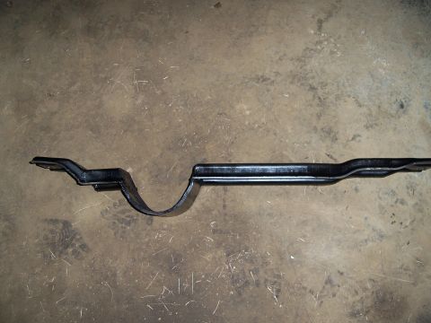 1983 Ford Bronco - A black metal crossmember, likely for a vehicle, lies on a concrete surface.