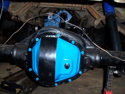 1983 Ford Bronco - Close-up of a rear axle housing painted gloss black with a light-blue differential cover carrying a black stripe across its face, sealed wi…
