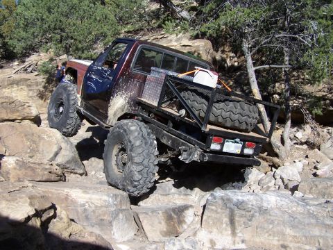 1981 Ford Bronco - Modified truck navigates a rocky trail with its front tire lifted.