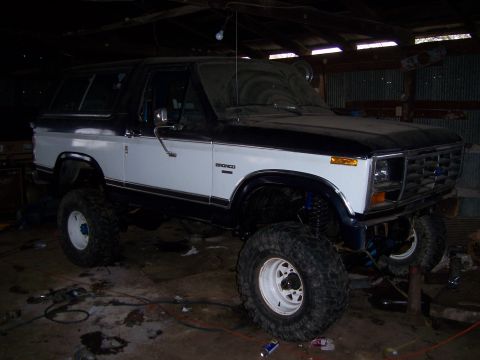 1983 Ford Bronco - This lifted two-tone 1983 Ford Bronco is parked inside a garage with its front end visible.
