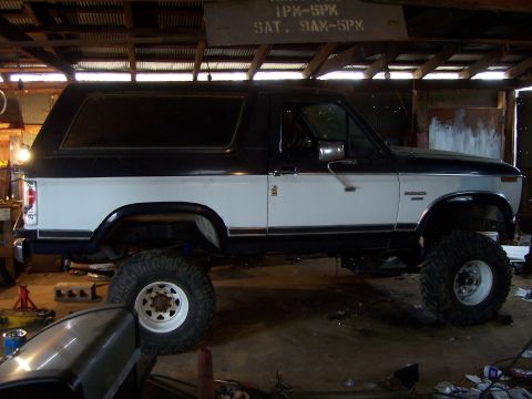 1983 Ford Bronco - This lifted Ford Bronco, likely from the early 1980s, is shown in a workshop setting with its distinctive two-tone paint scheme.
