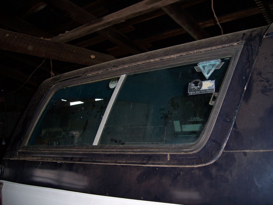 Rear side window of a dark colored vehicle with stickers on the glass