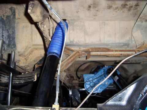 1983 Ford Bronco - Undercarriage view shows a blue shock absorber boot and a blue mechanical component, with visible brake lines.