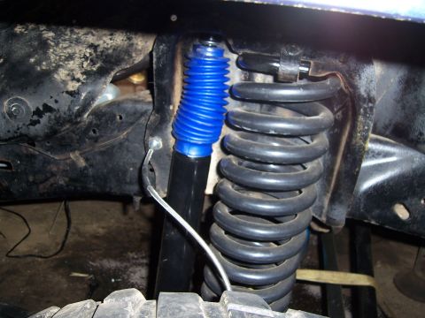 1983 Ford Bronco - Close-up view of a blue shock absorber and coil spring assembly.