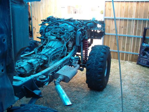 1994 Ford Bronco - The engine and chassis of a vehicle are shown with the body removed, revealing the drivetrain and suspension components.