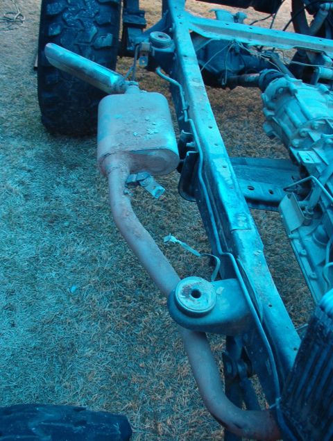1994 Ford Bronco - Close-up view of the exhaust system and frame of a vehicle, likely during body removal.