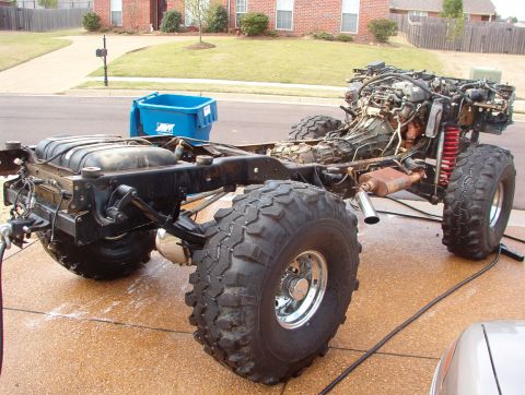 1994 Ford Bronco - The chassis of a vehicle, stripped of its body, is shown with its engine, large tires, and suspension components.
