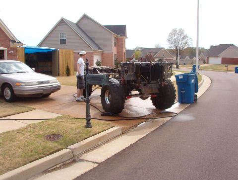 1994 Ford Bronco - A custom off-road vehicle chassis with oversized tires is being cleaned on a suburban driveway.