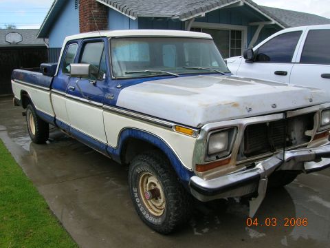 1985 Ford Bronco - This two-tone Ford pickup truck has a dented front bumper and appears to be a 1970s model.