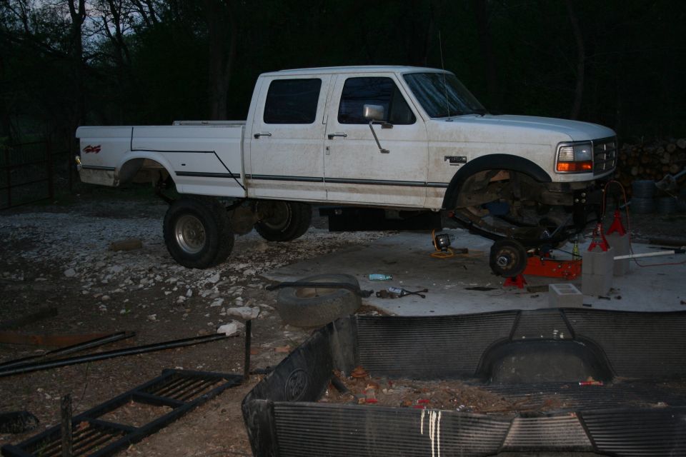Shackless. 
About where it will sit once the shackles are on it, probably about 2-4" higher, plus the tires' height. So overall the front will be about 10-14" higher.
