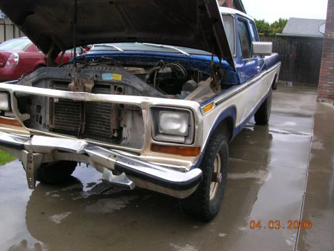 1985 Ford Bronco - This Ford F-Series truck has a damaged front bumper and its hood is open, revealing the engine compartment.