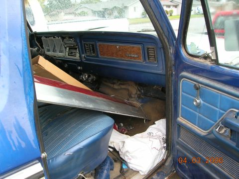 1985 Ford Bronco - Interior view of a blue truck, showing the dashboard and passenger seat area with various items.