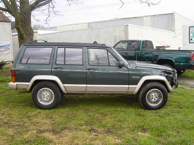 Side view of a green 1993 Jeep Cherokee parked on grass