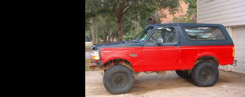 1993 Ford Bronco - A two-tone Ford Bronco is shown from the side, parked next to a garage.