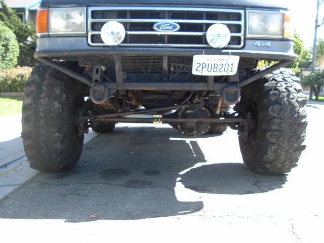 Front of a lifted Ford truck showing grille, driving lights and California plate