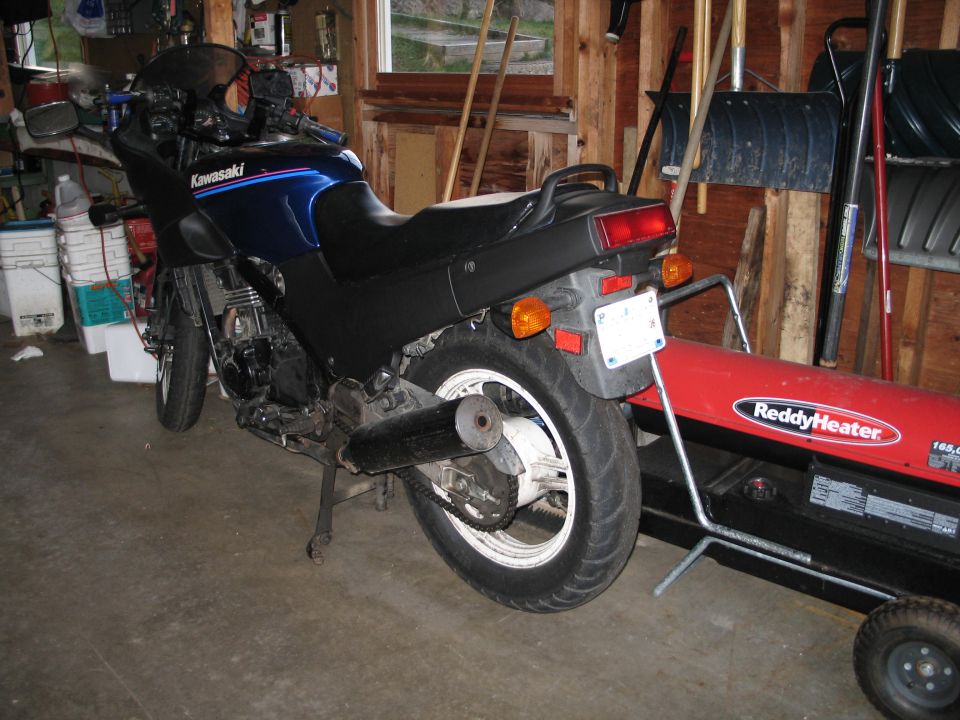 Black and blue Kawasaki motorcycle rear view parked in a garage