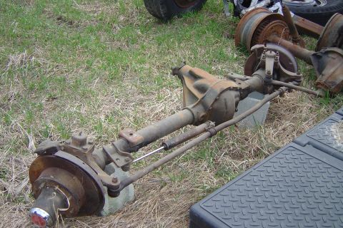 1980 Ford F-250 - A disassembled front axle assembly is shown lying on the ground outdoors.