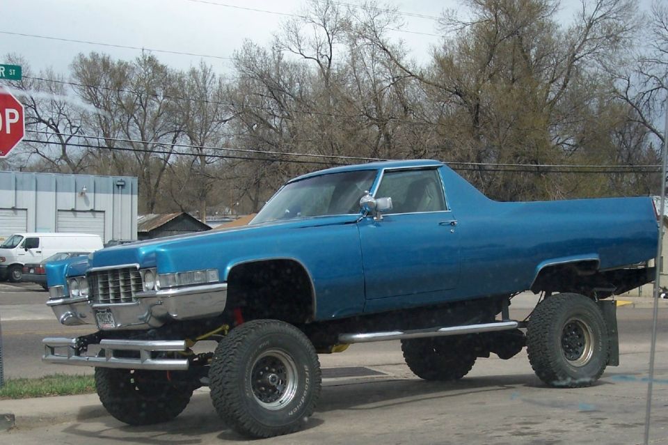 Blue Cadillac pickup truck with lifted suspension and large tires. Looks like a 1970 model